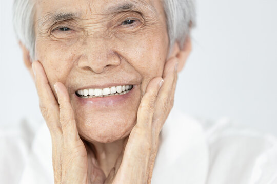 Happy senior woman is smiling confidently at beauty of new denture,false teeth in her mouth,beautiful old elderly showing new teeth after treatment,orthodontics,oral hygiene,dental health,care concep