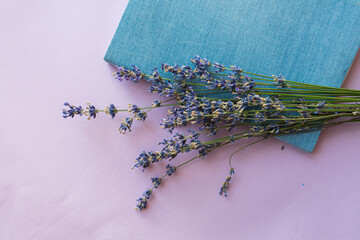 Lavender flowers and notepad on a bright purple background. Top view, flat lay.