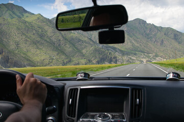 Man driving car on highway in Altai mountains. View from car window.