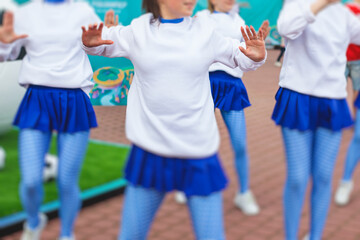 Female group of cheerleader in action, wearing white blue uniform with audience in the background...