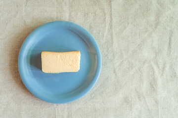 リネンのテーブルクロスに置かれた水色のお皿とベイクドチーズケーキ