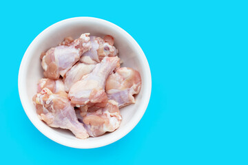 Fresh raw chicken wings (wingstick) in white bowl on blue background.