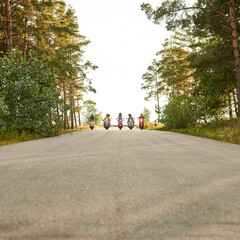 Young multiracial people riding colorful scooters in row