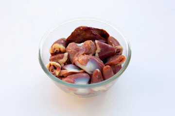 Mixed chicken entrails in glass bowl on white background.