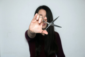 Beautiful brunette woman with long hair showing the scissors to the camera.