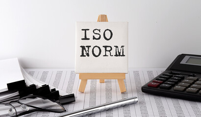 text ISO NORM on easel with office tools and paper.Top view. Business concept - obrazy, fototapety, plakaty