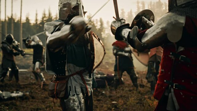 Epic Battlefield: Two Armored Medieval Knights Fighting with Swords. Dark Ages Army Warfare. Action Battle of Armored Warrior Soldiers, Killing Enemies. Cinematic Historical Reenactment. Slow Motion