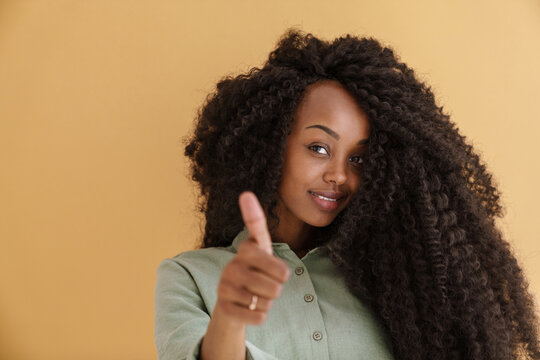 Young black woman with curly hair smiling and showing thumb up
