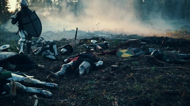 Medieval Knight Walking on Battlefield amidst Dead Enemies. Last Surviving Crusader, Soldier, Warrior after Battle. Destruction of War, Invasion, Crusade. Dramatic, Cinematic Historic Reenactment