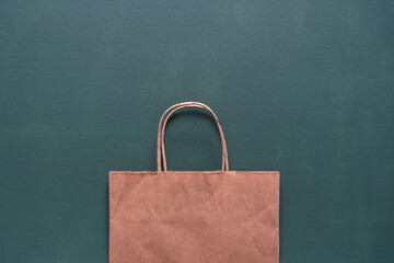 Eine braune Papier Einkaufstasche auf einem dunkel grünen Hintergrund. Flat lay, einkaufen.