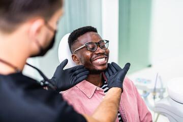 African American young man having a visit at the dentist's. He is sitting on chair at dentist office in dental clinic. - 446429045
