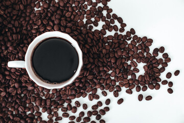 Cup of hot black coffee standing on fresh aromatic roasted coffee beans isolated on white background