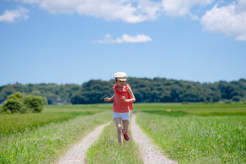 Obraz premium 夏のあぜ道を歩く子供