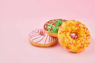 Doughnut with multicolored glaze on trendy pink background. Donut are traditional sweet pastries.