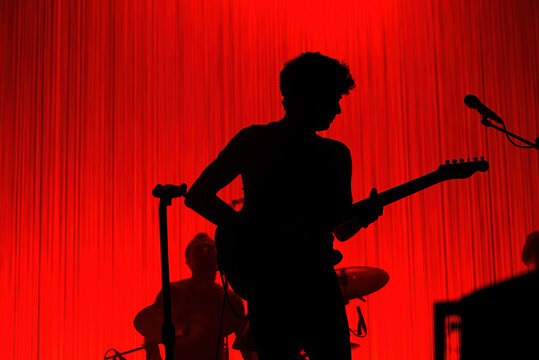 Unrecognizable silhouette of rock musician with guitar in a red background