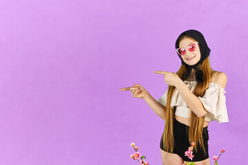 Young long hair woman shows something, point finger left at blue studio background. Girl pointing fingers left and smiling, showing advertisement.