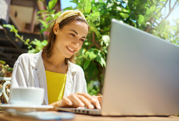 Close-up portrait young business woman working and typing on laptop computer, checking notification for laptop system, working in cafe during vacation
