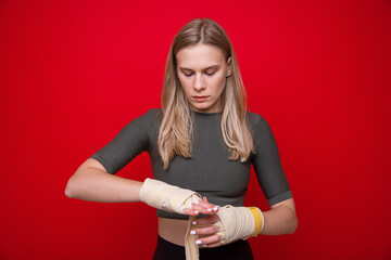Young athletic woman bandages her hands before boxing training