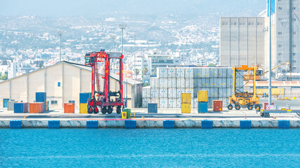 Obraz premium Two shipping container carriers in front of warehouse at port cargo terminal