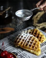 Vertical shot of freshly baked waffles and a male hand holding fresh coffee in jazzve