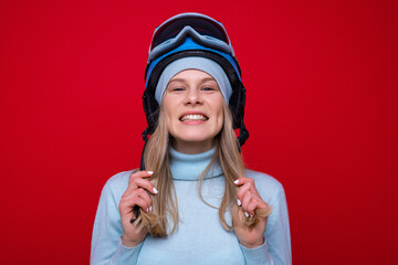 Portrait of a smiling young woman in a sweater, helmet and ski goggles