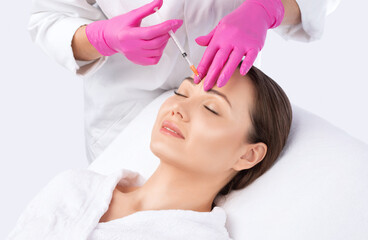Cosmetologist makes rejuvenating anti wrinkle injections on the face of a beautiful woman. Female...