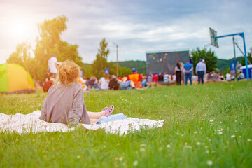 Girl sitting on the lawn watching a movie in the open air