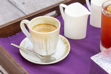 Coffee cup and milk on white plate with purple napkin
