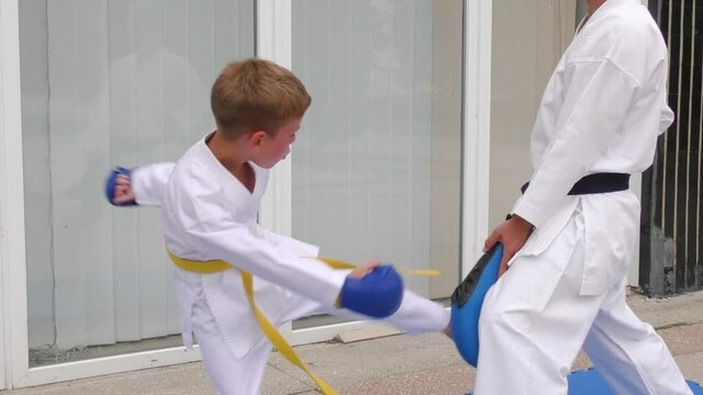 Boy kicks circular kick on blue exercise machine to lower level