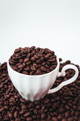 Cup with fresh aromatic roasted coffee beans isolated on white background. Cope space. Vertical