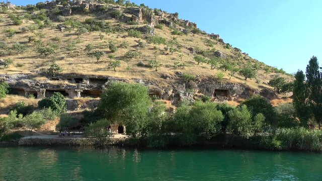 Halfeti, Sanliurfa, Turkey - 14th of June 2021: 4K Passing on boat along the rock tombs on the Euphrates riverbank
