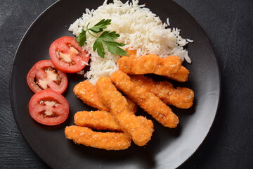 Chicken nuggets, rice and vegetables  on a black plate
