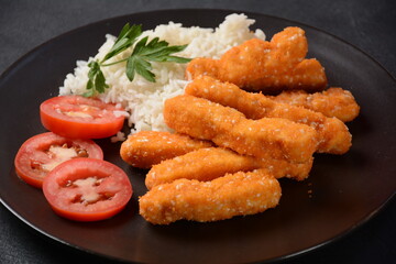 Chicken nuggets, rice and vegetables  on a black plate