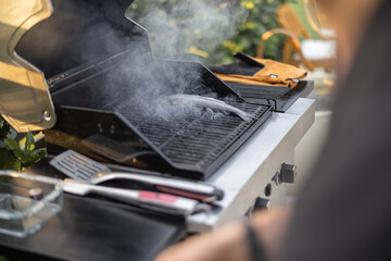 Fresh trout fish cooking on a gas grill outdoors, close-up