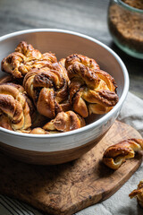 Bowl with freshly baked cinnamon yeast knot buns on dark background .
