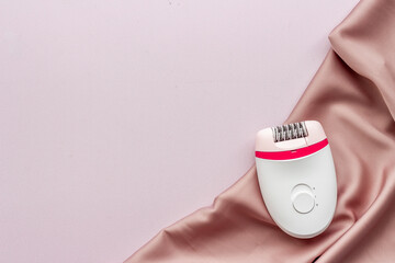 White epilator on soft silk. Hair removal and depilatory concept