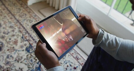 Composite of man sitting at home, watching sports event on tablet