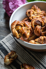 Bowl with freshly baked cinnamon yeast knot buns on dark background .