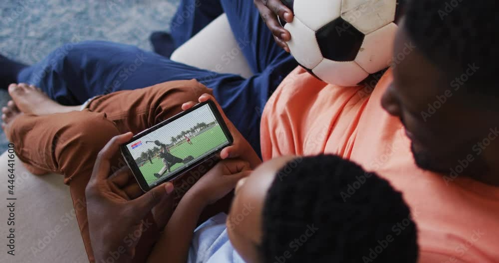 Canvas Prints Composite of father and son at home watching hockey match on smartphone