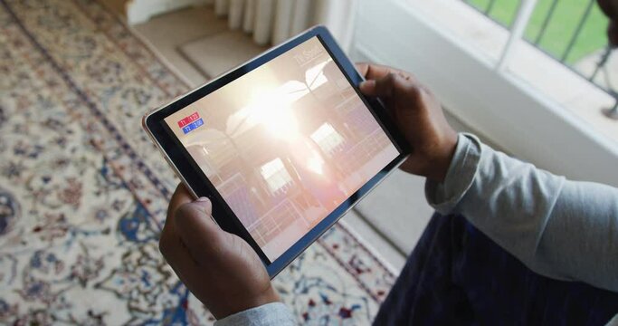 Composite of man sitting at home watching sports event on tablet