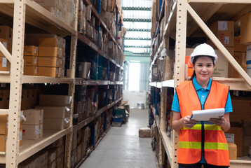 Portrait of smiling asian worker in helmets woman checking goods and supplies on shelves. In a...