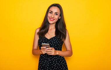 Cute modern confident young brunette woman is using her smart phone while she is isolated over...