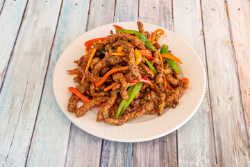 Caramelized beef strips with strips of red and green peppers, carrots and onions sauteed on white...