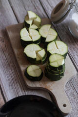 
cutting zucchini with a knife on a wooden cutting board. On the kitchen table