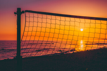 volleyball net on the beach against the background of the sea and sunset