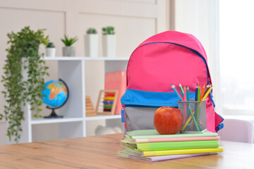 Backpack,apple, school supplies on the background of the school classroom .Back to school and kindergarten . The beginning of the school season.