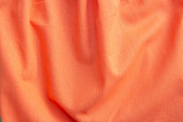 Beautiful orange fabric texture with folds and contrasting shadows . Draped background of bright...