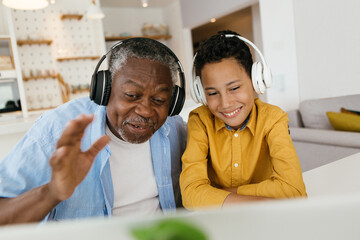 Happy African grandfather and grandson sitting together at home and listening to good music....