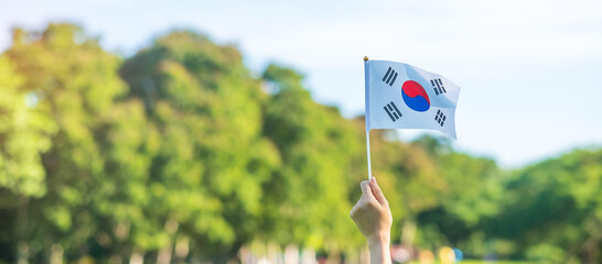 hand holding Korea flag on nature background. National Foundation, Gaecheonjeol, public Nation holiday, National Liberation Day of Korea and happy celebration concepts