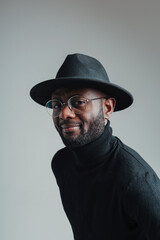 Happy handsome african american man in glasses and a hat stands half-turned looking at the camera
